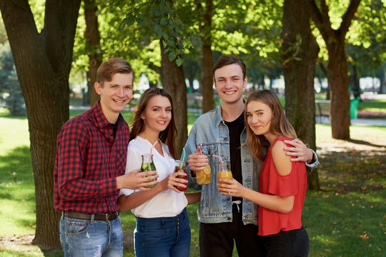 Group of happy young people enjoys detox cocktails and spend time together at summer. Friendship, youth lifestyle, vegetarian diet, fitness food on the go, successful weight loss concept