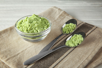 Wheat grass powder in bowl and spoons on table