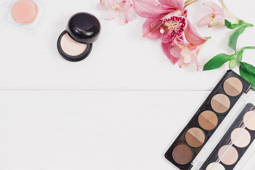 Decorative flat lay composition with makeup products, cosmetics and flowers. Flat lay, top view on wooden background.