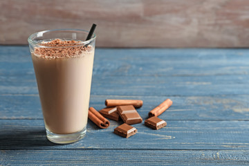 Glass with chocolate protein shake on wooden table