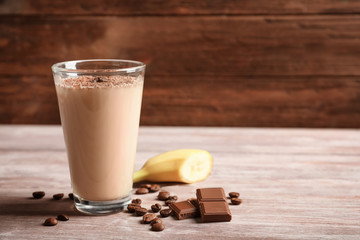 Glass with chocolate protein shake on wooden table