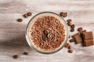 Glass with chocolate protein shake on wooden table, closeup