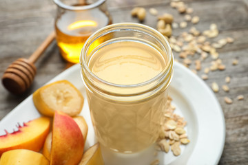 Jar with protein shake and plate with fruits on table, closeup