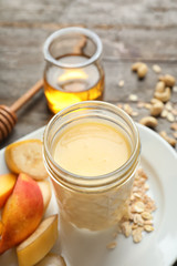 Jar with protein shake and plate with fruits on table, closeup