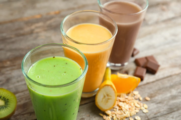 Fototapeta premium Glasses with different protein shakes on wooden table, closeup