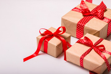 Square rectangular gift boxes wrapped in craft paper with satin red ribbon bow for Christmas...