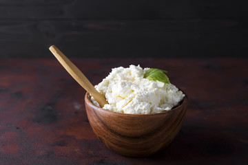 Fresh cottage cheese in a wooden bowl and spoon on