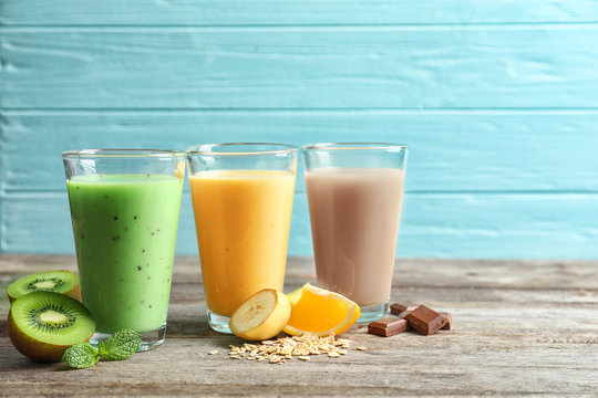Glasses with different protein shakes on wooden table