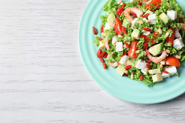 Plate with delicious goji berry salad on wooden background