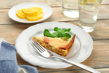 Plate with piece of salmon quiche pie on table