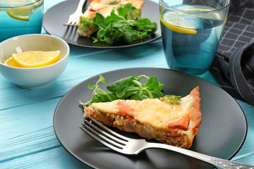 Plate with piece of salmon quiche pie on table