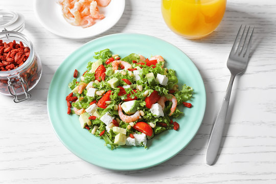 Plate with delicious goji berry salad on table