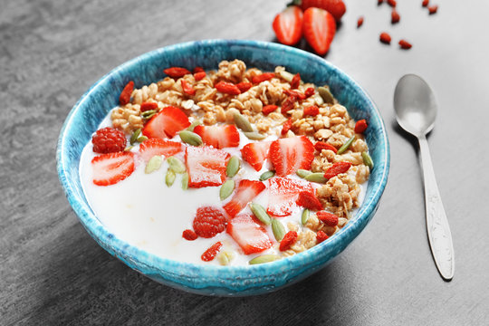 Oatmeal with goji berries and milk in bowl on grey background