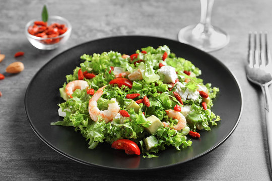 Plate with delicious goji berry salad on grey background