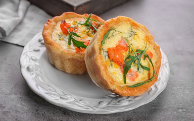 Plate with tasty salmon tartlets on table