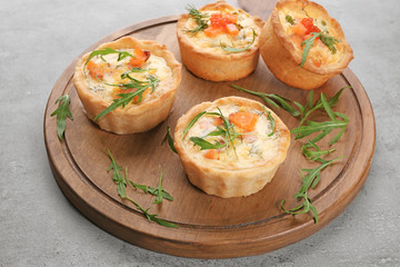 Board with tasty salmon tartlets on table