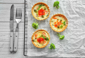 Baking grid with tasty salmon tartlets on table