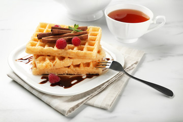 Plate with delicious cinnamon waffles on table