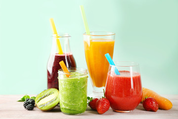 Glassware with delicious smoothies on table against color background