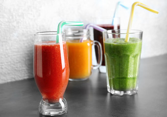 Glassware with smoothies on table against light background