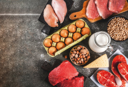 Healthy food background. Selection of protein sources: beef and pork meat, chicken  filet, salmon fish, egg, beans, nuts, milk. Top view copy space, dark background