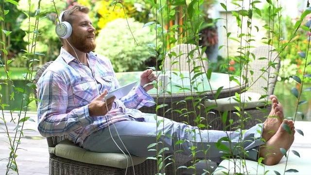 Man having fun while relaxing in the garden and listening music
