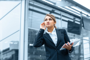 Successful businesswoman or entrepreneur using a digital tablet computer, standing in front of his office.