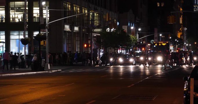 A night time view of pedestrians in a Manhattan 6th Avenue crosswalk.  	