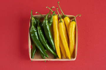 green and yellow chili peppers, popular spices concept - decorative pattern of red hot chili with green tails on red background, beautiful red collage of freely lying peppers, top view, flat lay