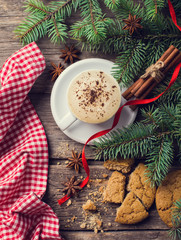 A cup of coffee with the branches of the Christmas tree on a wooden table
