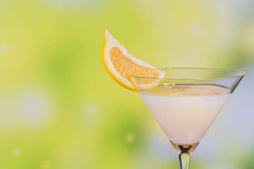 Glasses of cream liqueur with lime and lemon on green background with reflection.