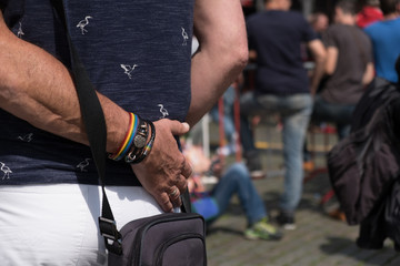 Two gay men embrace in a crowd in the closing day of the Antwerp Gay Pride festival. Homosexual couple in the Grote Markt. Gay man puts arm around partner's waist at outdoor festival.