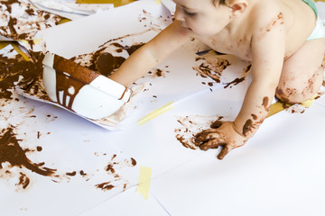 baby painting with hands with chocolate