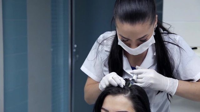 In the beauty salon, the cosmetologist performs the procedure for the mesotherapy of the hair