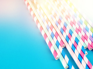 Naklejka premium Drinking straws for party on blue pastel background with copy space. Top view of colorful paper disposable eco-friendly straws for summer cocktails.