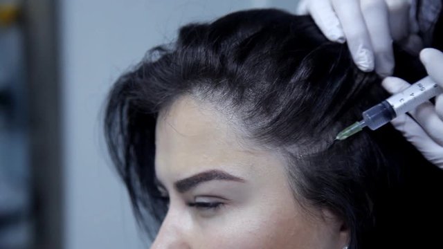 The doctor-cosmetologist performs the procedure of mesotherapy, injections into the skin of the head. Close-up