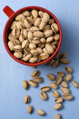 Red Cup of Pistachios on Blue Background
