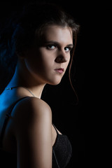 beautiful sad young woman on black background looking over shoulder at camera