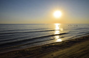 Fototapeta premium Sea sunset. People bathe in the evening at sunset in the sea.