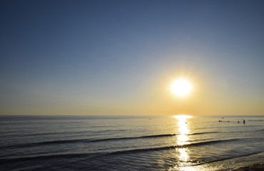 Fototapeta premium Sea sunset. People bathe in the evening at sunset in the sea.