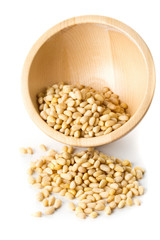 Heap of raw, uncooked pine nuts in wooden bowl