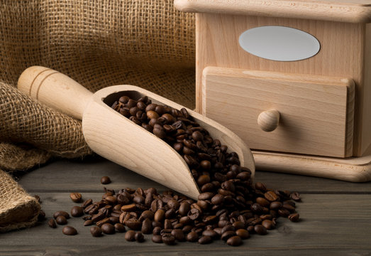 Coffee beans in wooden scoop with coffee bean grinder