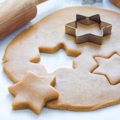 Making gingerbread cookies. Dough, metal cutter and rolling pen on a wooden table, square format