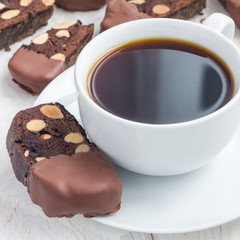 Homemade dark chocolate biscotti cookies with almonds, covered with melted chocolate, and cup of coffee, square format