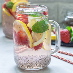 Healthy detox chia seed drink with strawberry, lemon and mint in glass jar, square format