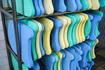 Colorful foam kickboards on silver metal rack by swimming pool