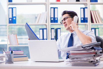 Businessman with excessive work paperwork working in office