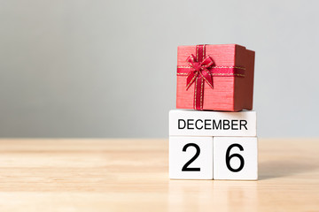 Wooden block calendar 26 December and red color gift box on wood table with white wall background,...