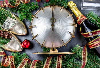 NEW YEAR CELEBRATION. Traditional put money to shoe for have money en New Year. Flat lay composition with vintage clock, shoes with dollars, champagne, Christmas decorations