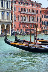 Fototapeta na wymiar Gondolas in front of old houses by Canal Grande in a summer day in Venice